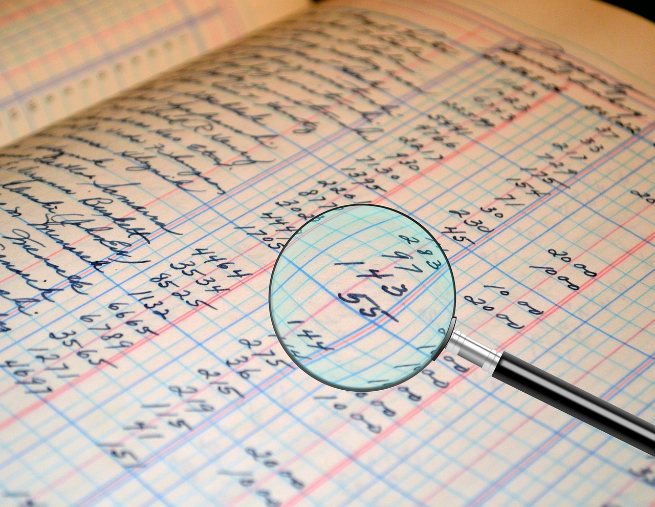 A magnifying glass focusing on financial figures on a printed statement.