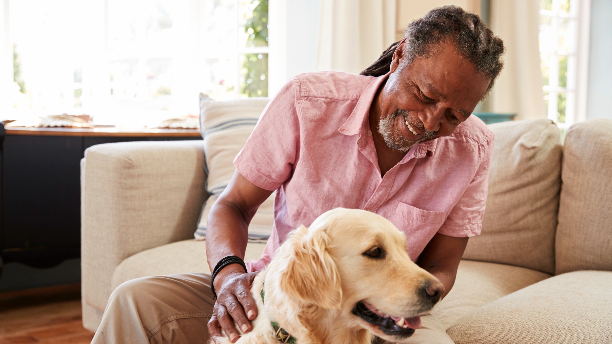 A senior man relaxing in a living room with his golden retriever.