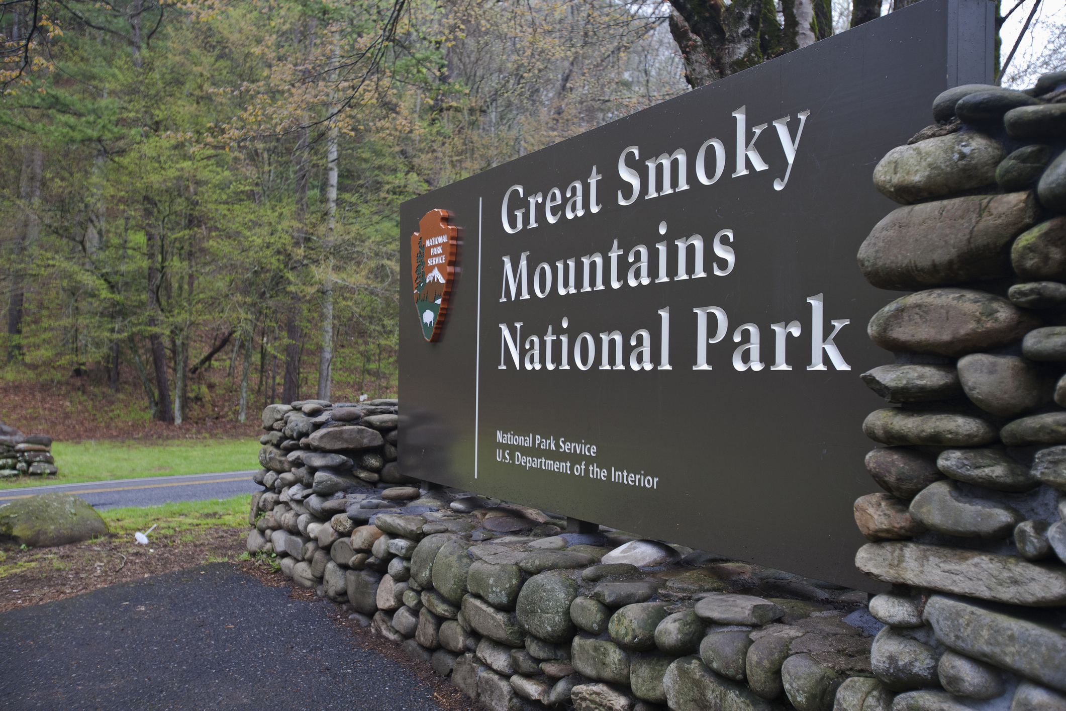 Entrance sign to the Great Smoky Mountains National Park surrounded by trees.