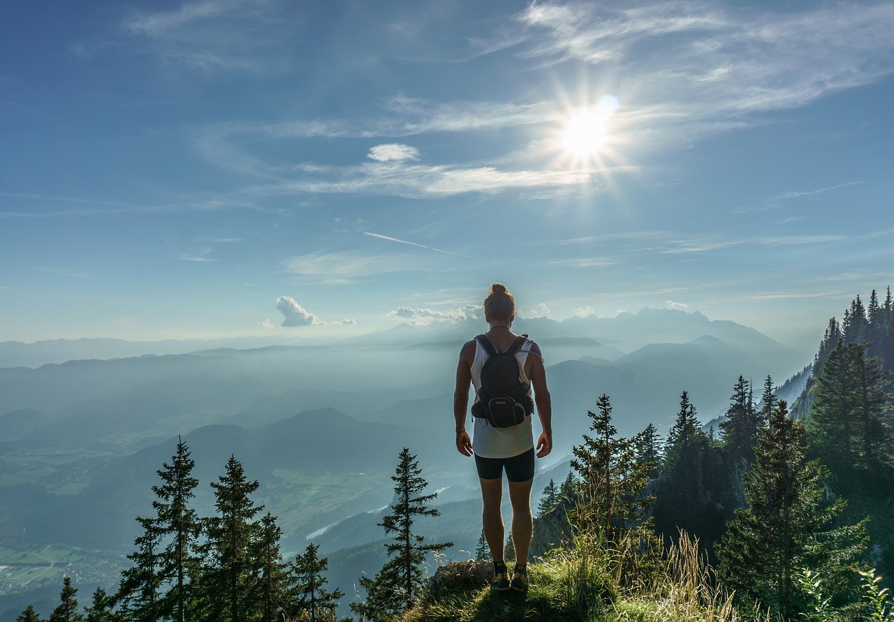 A person standing on a mountain peak looking at the horizon representing financial success.