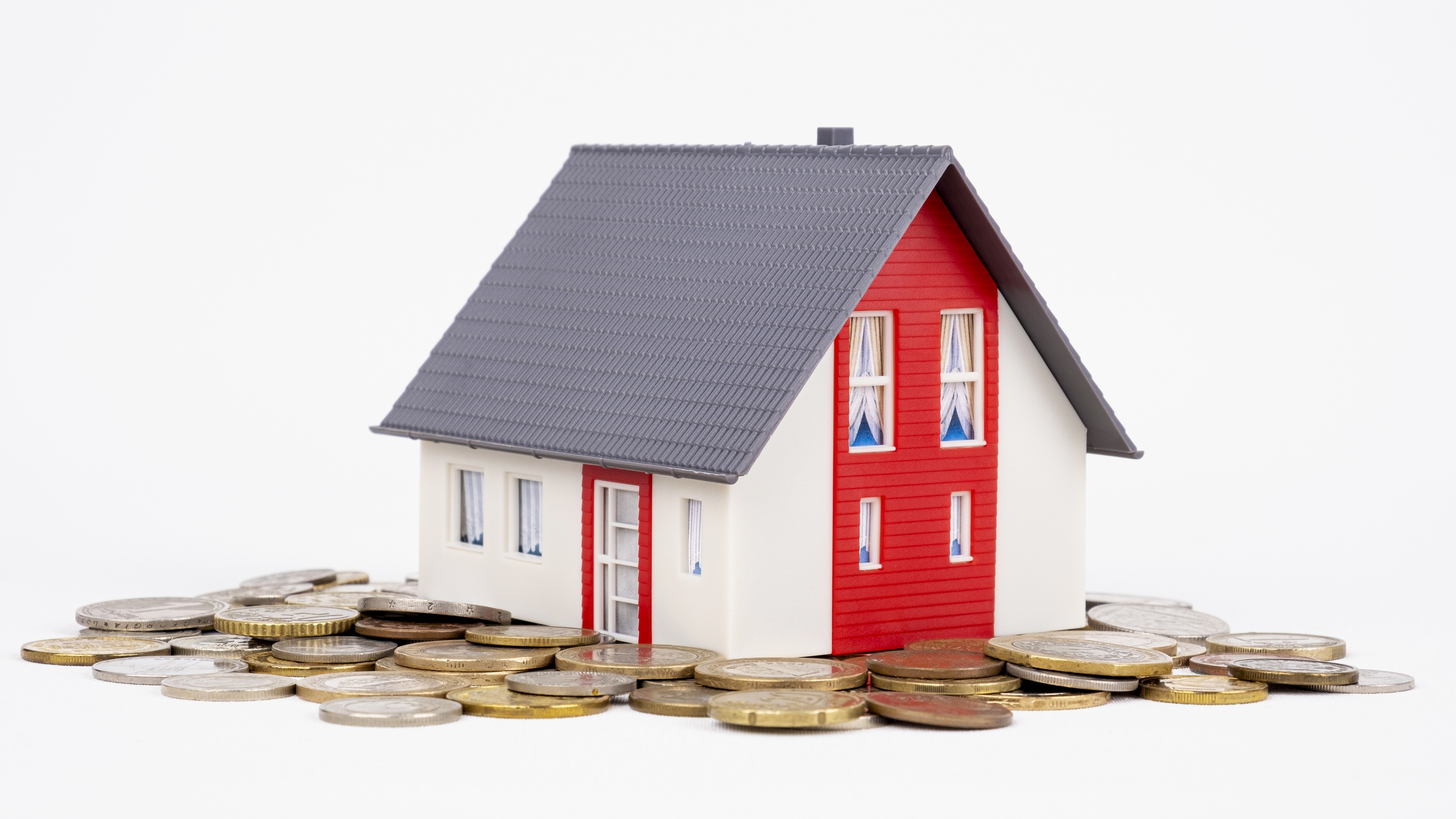 A conceptual image of a model house placed on a stack of coins.