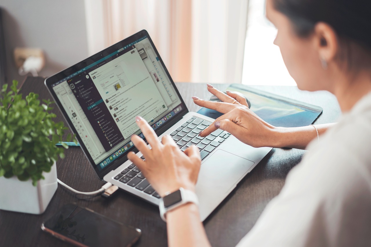 A couple sitting together in a home office looking at a laptop, discussing their joint finances.