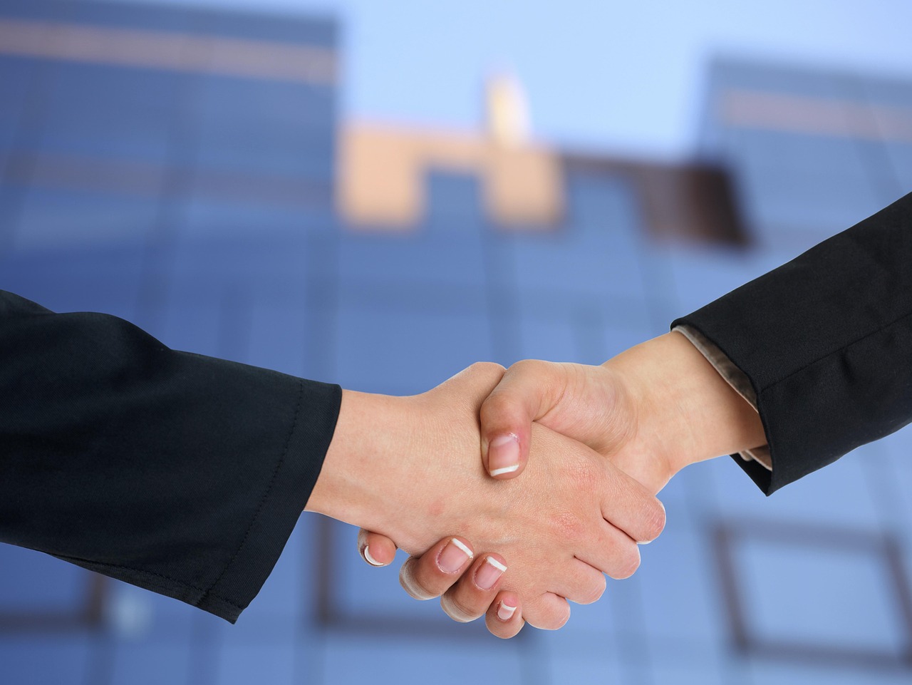 Two professionals in a meeting discussing financial paperwork over a wooden table.