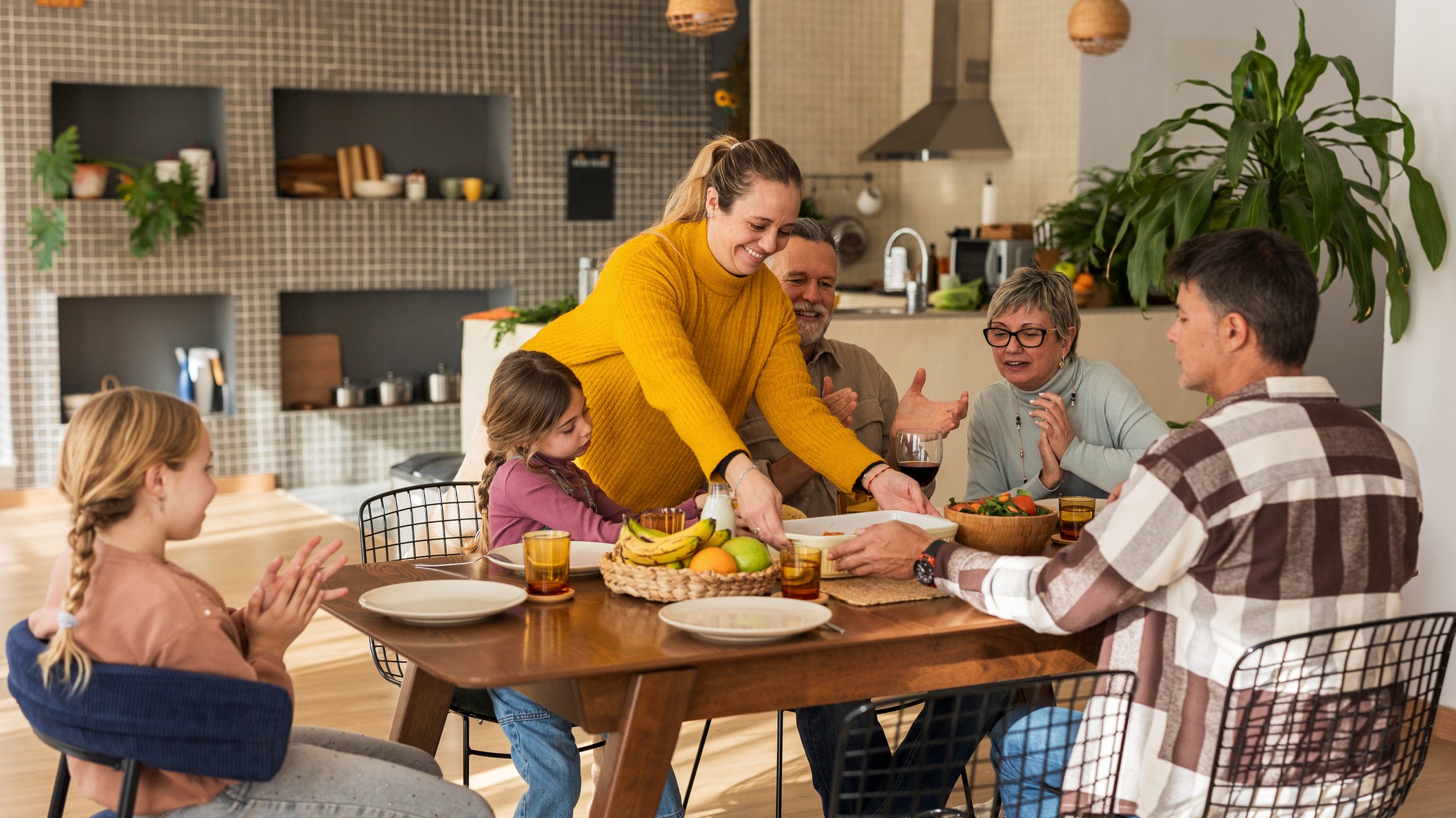 Three generations of a family gathered around a dinner table in a spacious home.