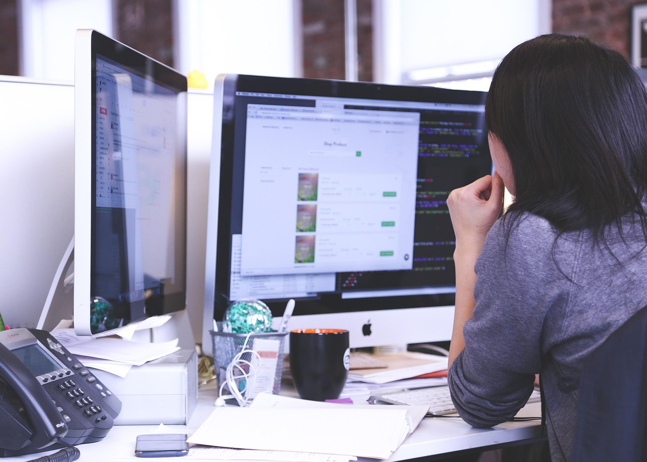 A young professional analyzing data on a laptop in a bright, modern workplace.