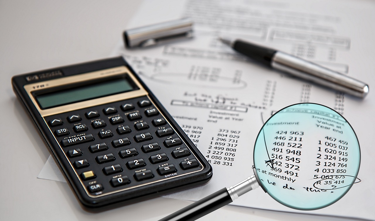 A person reviewing a detailed financial document with a magnifying glass.
