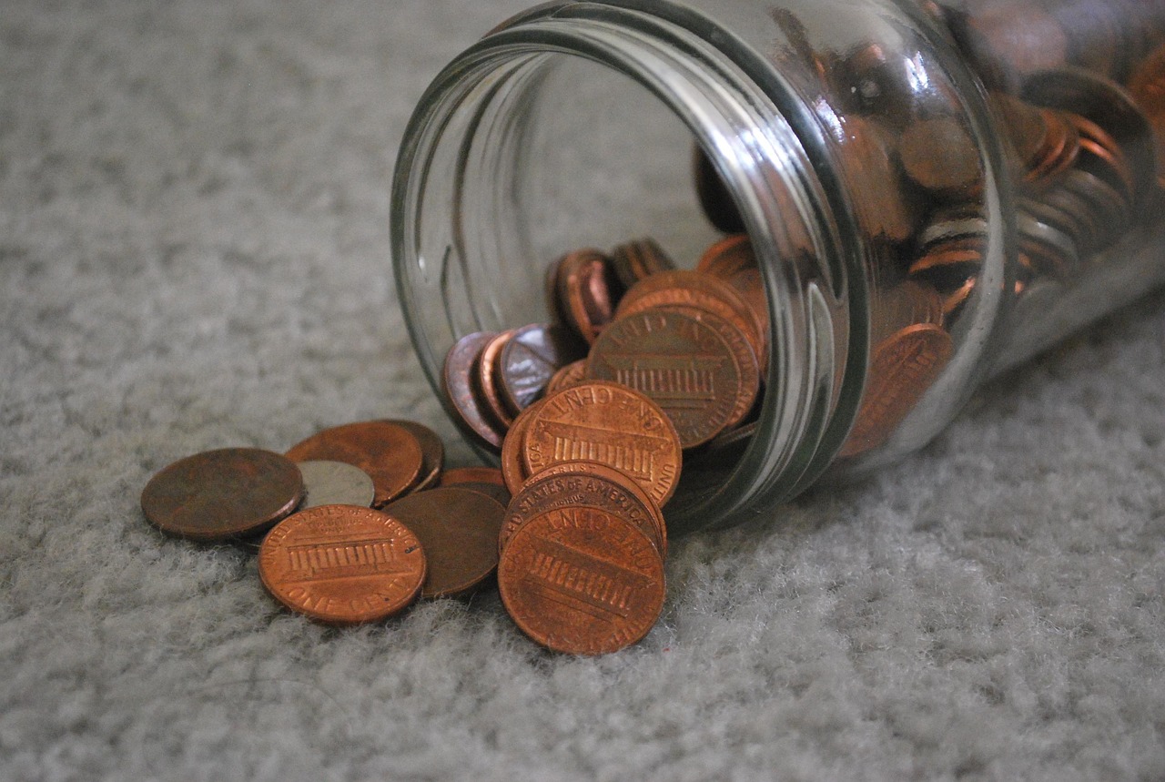 Coins accumulating in a glass jar with a small plant growing out to symbolize yield.