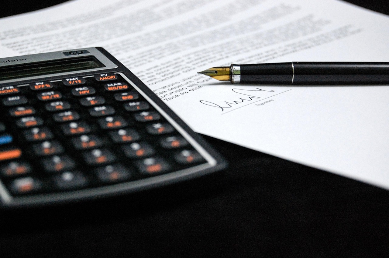 A calculator next to stacks of coins and a financial chart on graph paper.
