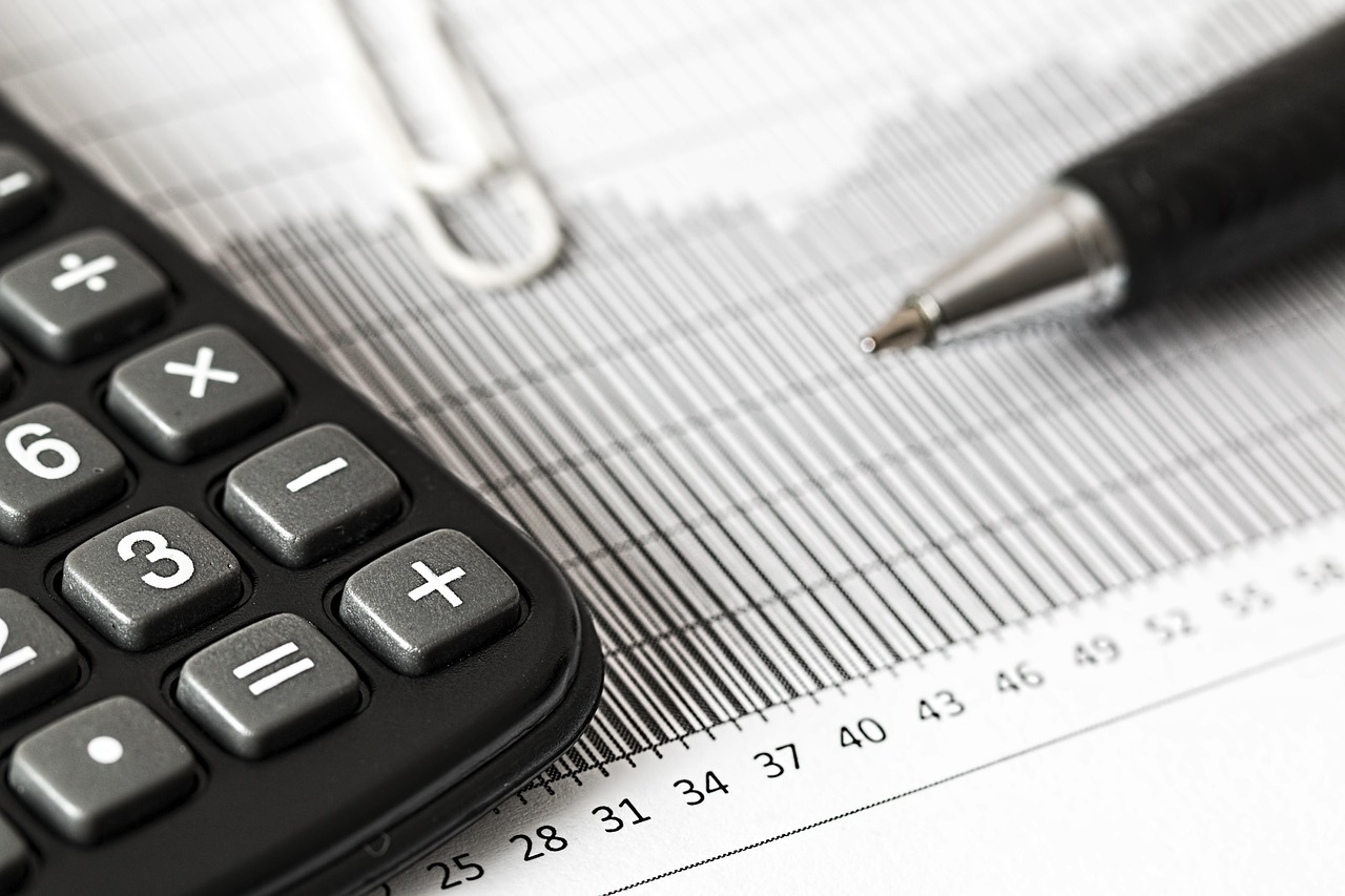 Organized financial documents on a desk with a pair of reading glasses and a pen.