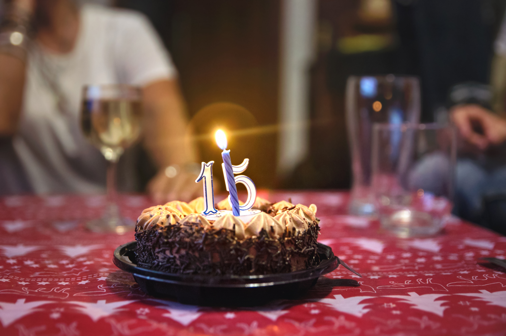 A chocolate cake with a candle in the shape of the number 15.