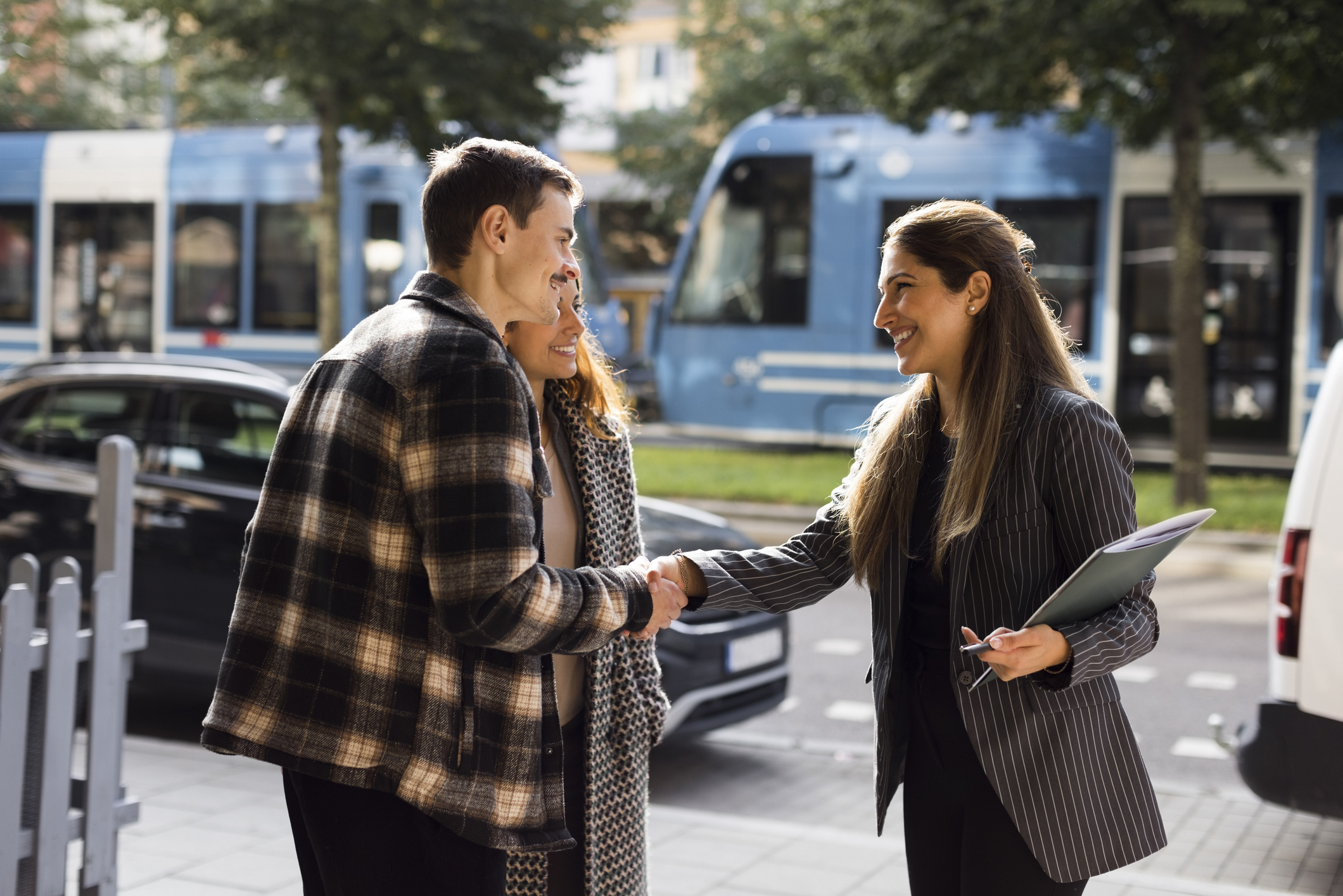 A man shaking hands with a real estate professional outdoors near a residential property.