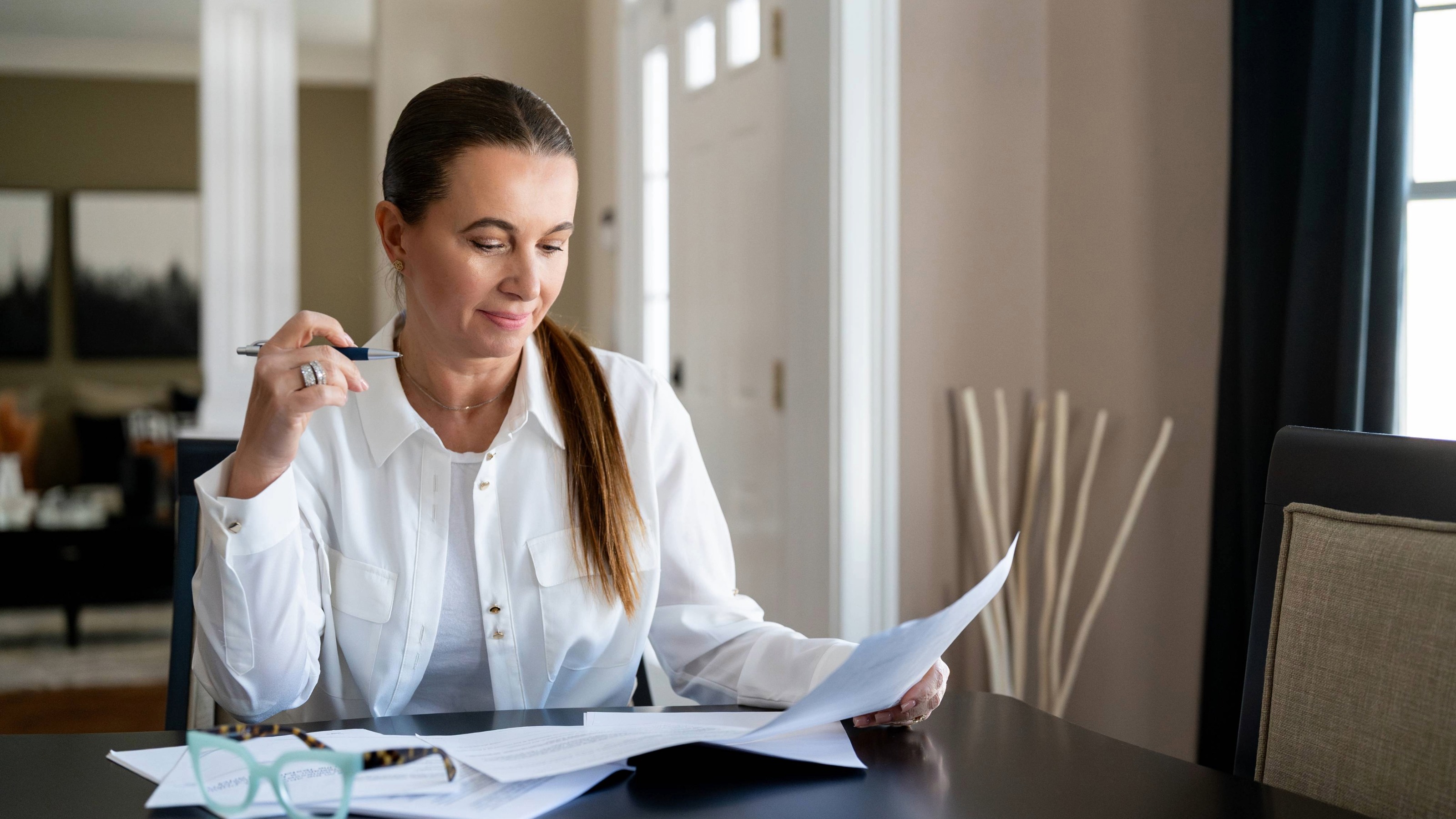 A woman reviewing financial papers with a look of confidence and clarity.
