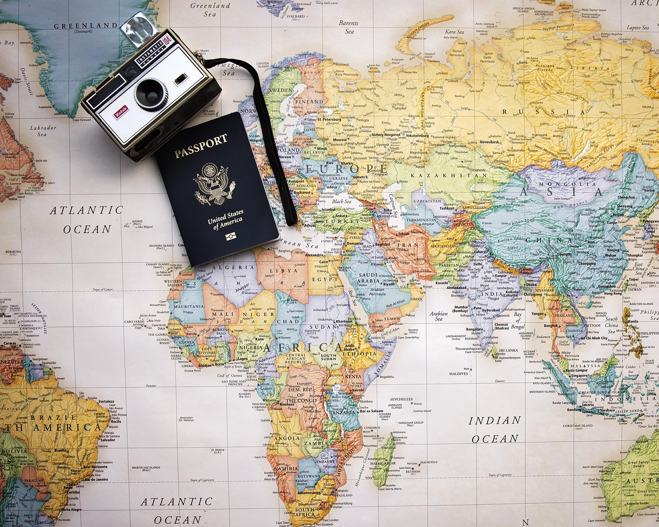 A flat lay of travel essentials including a passport, suitcase, and camera on a clean background.