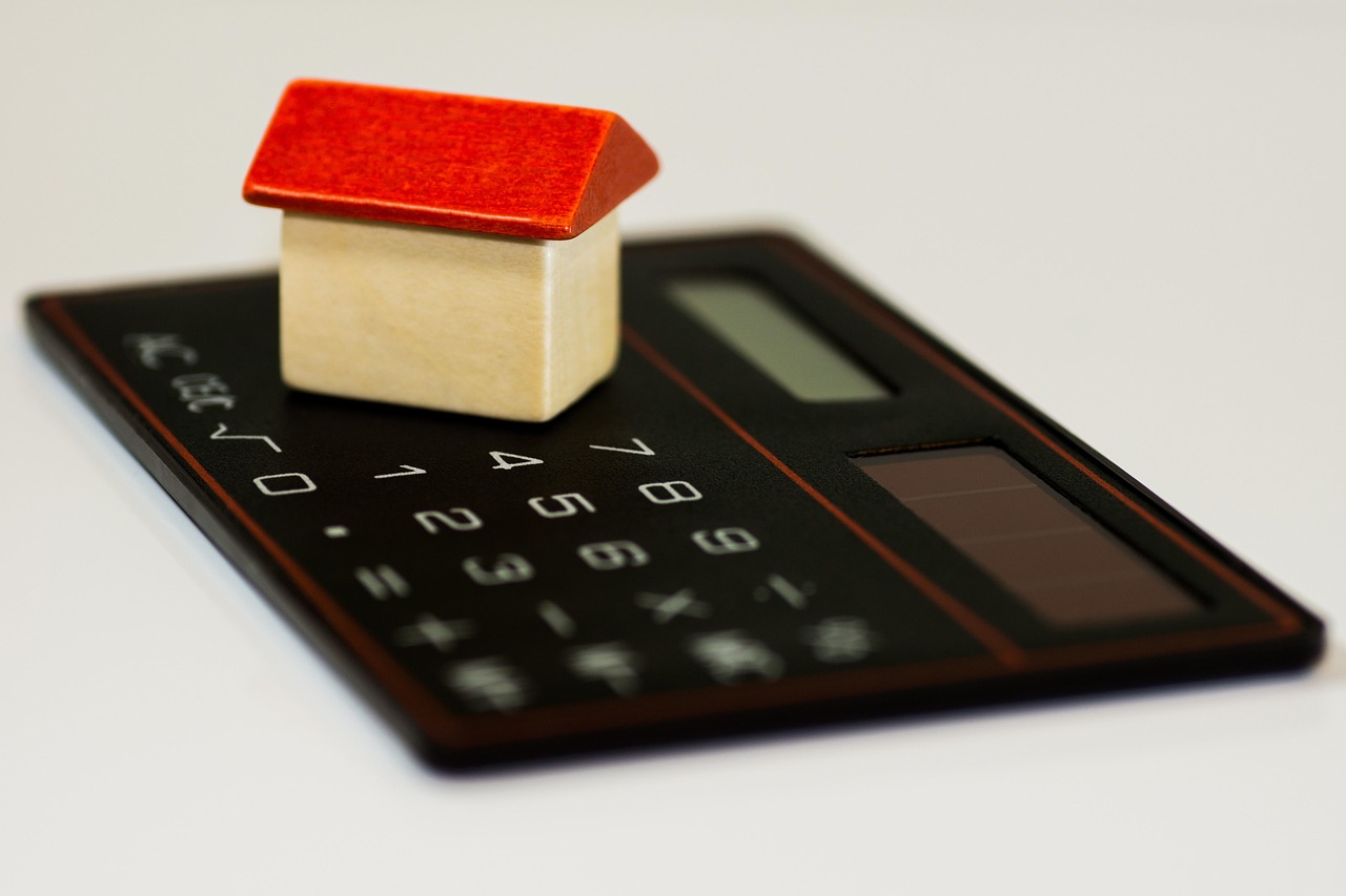A modern calculator next to a small balance scale depicting the ratio of debt to available credit.