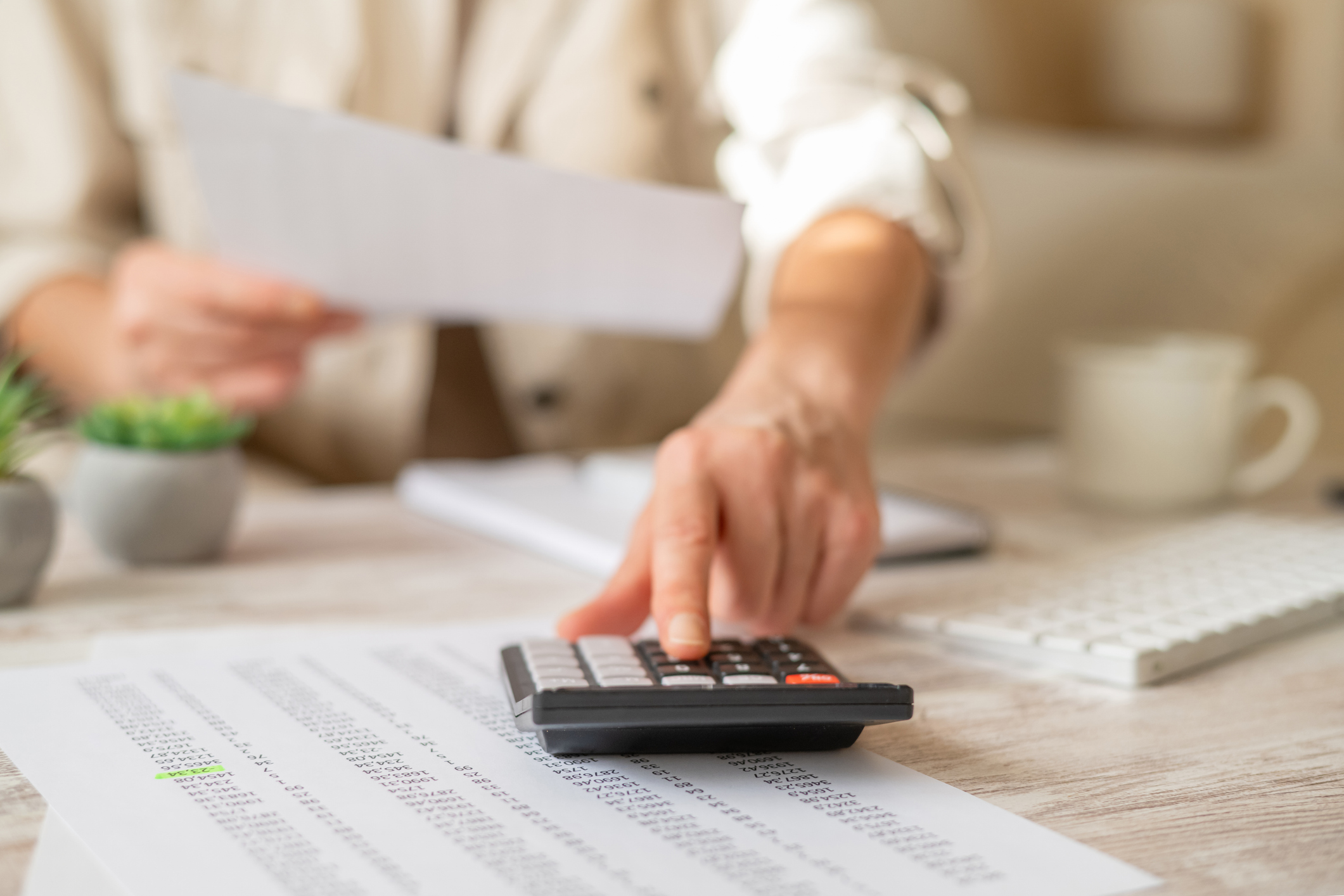 A person using a calculator and reviewing financial documents to plan a family budget.