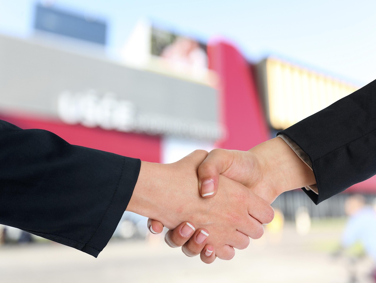 A handshake between a professional advisor and a client in a bright office.