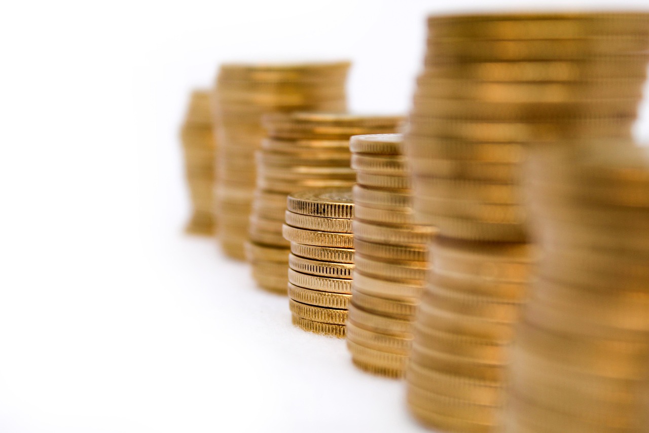 A small yellow umbrella shielding a stack of coins, representing the protection of an emergency fund.
