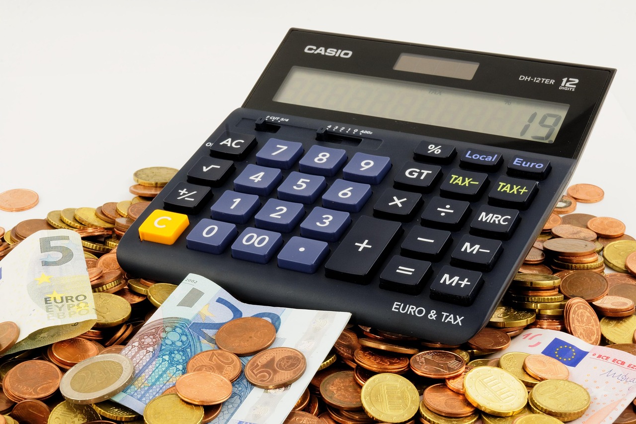 A calculator next to stacks of coins representing financial growth and cost analysis.