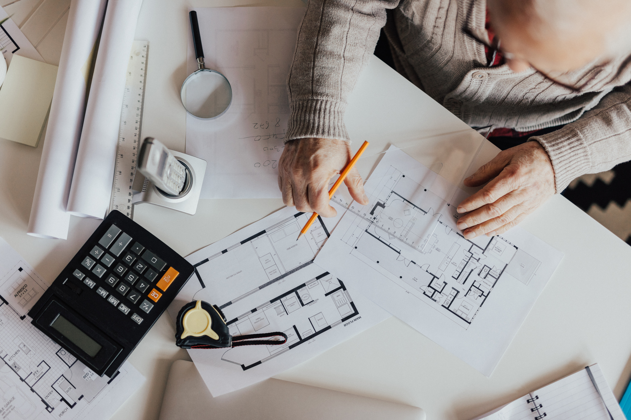 Top-down view of a person reviewing renovation blueprints and financial notes.