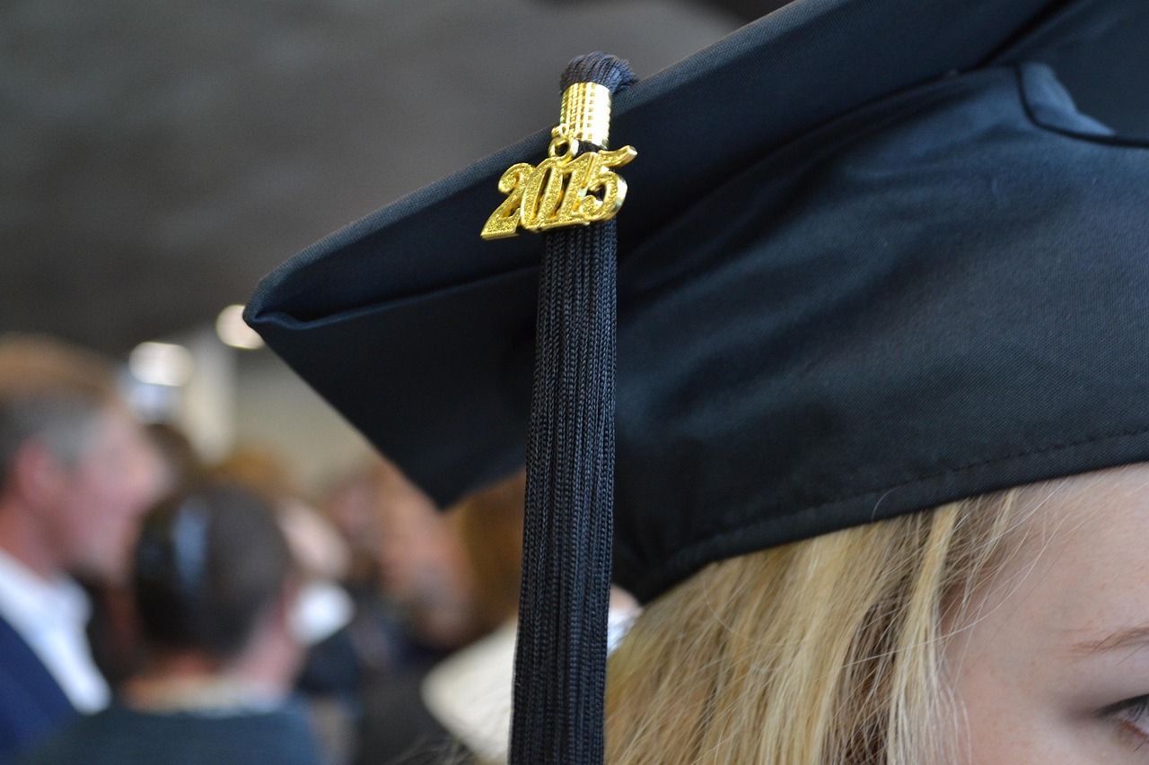A graduation mortarboard next to modern car keys, representing student and auto loan priorities.