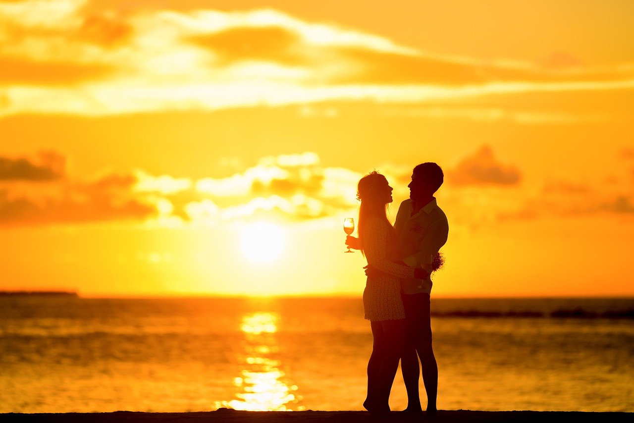 A happy senior couple walking along a beach during a golden sunset.