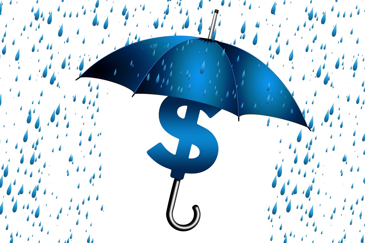 An umbrella protecting a small pile of coins from rain representing an emergency fund.
